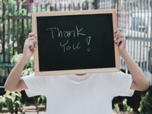 Man holding a small board with Thank You written on it