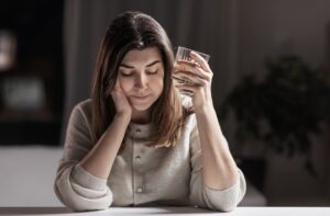 Depressed woman holding a glass of whiskey 