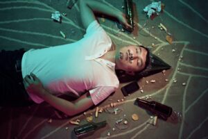 Drunk man lying down on the floor surrounded by beer bottles and party decor